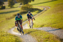 Zwei junge Männer fahren auf Gravel bikes über Feldweg, Münsing, Bayern, Deutschland