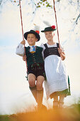 Kids in  Traditional bavarian clothes on a swing, Ammerland, bavaria, Germany