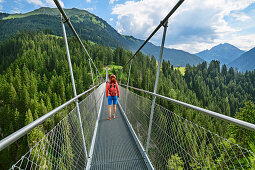 Woman walking on suspension bridge, Holzgau, Lechweg, valley of Lech, Tyrol, Austria