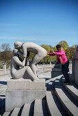 japanische Touristin in pinkem Oberteil dass an den Po einer Skulptur, der Vigeland Skulpturenpark des Bildhauers Gustav Vigeland, Frognerpark, Oslo, Norwegen, Skandinavien, Europa