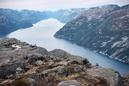 Wanderer sitzen an Felskante beim Preikestolenund genießen den Ausblick auf den Lysefjord, Provinz Rogaland, Norwegen, Skandinavien, Europa