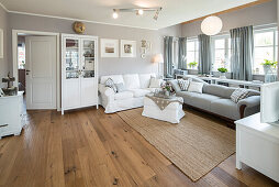 Modernes nordisches Wohnzimmer im Einfamilienhaus mit weiß und grau gewählten Möbeln und Holzfußboden, Korbach, Hessen, Deutschland, Europa