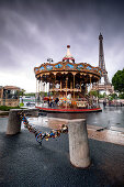 Carousel in front of the Eiffel Tower in rainy weather; in the foreground, love-locks are fastened to the chain of street-bluffing; Paris; Île-de-france; France