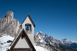 Bell tower of the chapel of San Giovanni Gualberto on the Passo di Giau in winter, in the background view of the Dolomites, Belluno, Italy