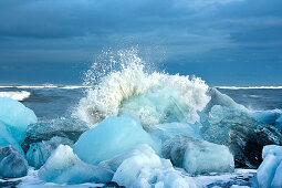 A wave breaking on the icebergs on Diamond Beach in southeast Iceland, Breidamerkursandur, Iceland, Europe