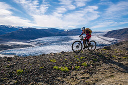 Mountainbiker fährt an einem kleinen Gletscher entlang, Island