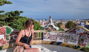 Frau auf Mosaikbank mit Ausblick auf die Stadt vom Park Guell in Barcelona\n