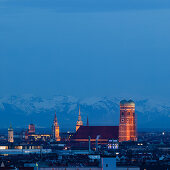 Munich city skyline with illuminated Frauenkirche and snowy Alps in the background at night