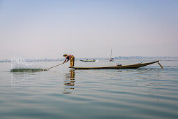 Fisherman on small boat with long stick for fishing on Inle Lake, Heho, Myanmar