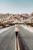 Frau läuft auf Straße im Joshua Tree National Park, Los Angeles, Kalifornien, USA, Nordamerika