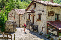 Woman hiking goes through village of Bulnes, Bulnes, Picos de Europa, Picos de Europa National Park, Cantabrian Mountains, Asturias, Spain