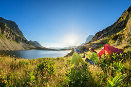 Man and woman sit by tent on Lac Roumassot and have breakfast, Pic du Midi d´Ossau in the background, Lac Roumassot, Pyrenees National Park, Pyrénées-Atlantiques, Pyrenees, France