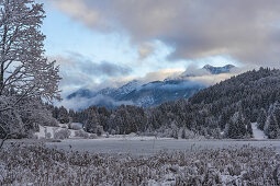 View over the frozen Geroldsee to snow-covered landscape, Krün, Bavaria, Germany.