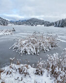 View over the frozen Geroldsee to snow-covered landscape, Krün, Bavaria, Germany.