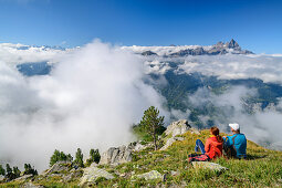 Mann und Frau beim Wandern sitzen auf Bergwiese und blicken auf Wolkenmeer mit Dents du Midi, vom Dent de Morcles, Berner Alpen, Vaud, Waadtland, Schweiz