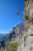 Woman climbs on overhanging ladder on adventure via ferrata Gemmi, Gemmi, Bernese Alps, Valais, Switzerland