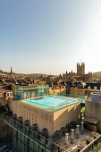 Blick auf den Außenpool auf dem Dach vor der Kulisse alter Türme und Gebäude, Bath, Großbritannien