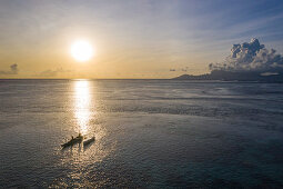 Luftaufnahme eines Auslegerkanus in der Lagune bei Sonnenuntergang mit Insel Moorea in der Ferne, nahe Papeete, Tahiti, Windward Islands, Französisch-Polynesien, Südpazifik