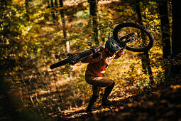 Mountain biker carries his bike through autumn forest, mountain biker, autumn, forest