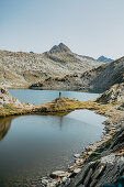 Mountaineer stands at a lake in the middle of the Swiss mountain range, Switzerland, mountains, lake, hiking,