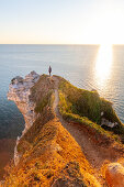 A woman looks out on the alabaster coast at Étretat and looks out over the sea, Normandy, France.