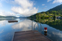 View over Lake Millstatt from the beach on the east bank of the alpine mountain and cultural landscape, Döbriach, Carinthia; Austria, Europe.