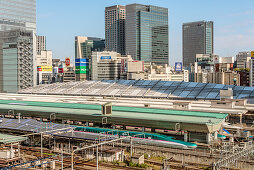 View of Tokyo Central Station with Shinkansen trains and the skyline of Marunouchi, Tokyo, Japan