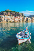 Blick auf Fischerboot und mittelalterliche Häuser von Cefalu, Cefalu, Sizilien, Italien