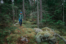 Man hiking through forest with moss covered ground in Tyresta National Park in Sweden