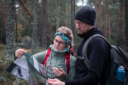 Woman and man reading hiking map while hiking in the forest in Tiveden National Park in Sweden