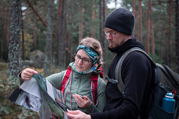 Frau und Mann lesen Wanderkarte beim Wandern im Wald im Tiveden Nationalpark in Schweden\n