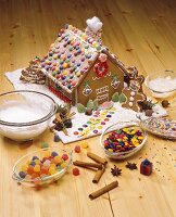 Gingerbread house with bowl of decorating ingredients