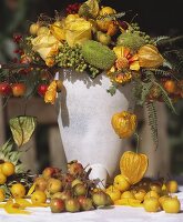 Autumnal flower arrangement with fruit in stone vase