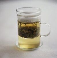 Grüner Tee mit Teeblättern im Glas