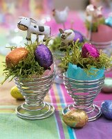 Eierbecher mit gefärbten Eierschalen, Moos und Schokoeiern