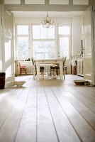 View through double doors of kitchen-cum-living room with antique chairs and white-painted dining table