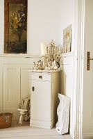 Silverware and candle on cabinet in corner of room with half-height wood panelling