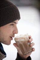 Young man drinking cocoa with whipped cream