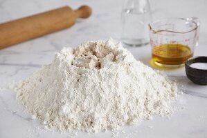 Baking ingredients (flour, yeast, salt, water, oil) and rolling pin
