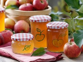 Bemalte Gläser mit Apfelgelee und frische Äpfel