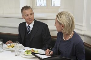Geschäftsmann spricht mit Sekretärin beim Essen im Restaurant