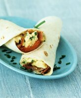 Two tortilla wraps filled with egg, bacon and chives