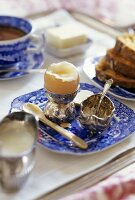 Boiled egg, salt, bread, butter and tea on breakfast tray