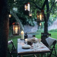 Laid table out of doors at twilight with lanterns