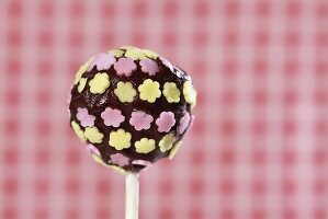 A cake pop, chilled and decorated with chocolate and sugar flowers