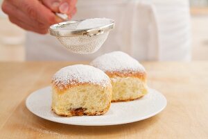 Buchteln (baked, sweet yeast dumpling) being dusted with icing sugar