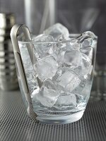 Ice cubes and ice tongs in a glass container