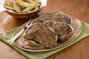 Platter of Grilled Angus Rib Eye Steaks; Oven Fries
