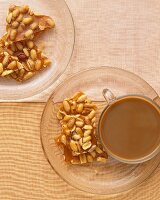 Erdnuss-Brittle mit einer Tasse Kaffee