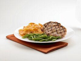 Gegrillte Schweinekoteletts mit grünen Bohnen und Kartoffelscheiben